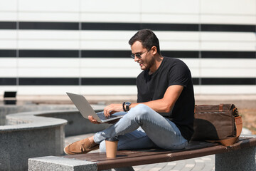 Poster - Handsome man using laptop on bench outdoors