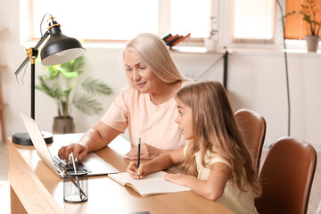 Poster - Little girl with her grandmother doing lessons at home