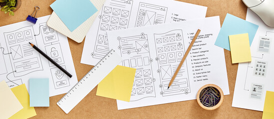 Web design concept banner. User experience designer desk with numerous website wireframe sketches and sitemap. Top view