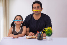 Father And Daughter Having Fun With Holding Pencil Between Lip And Nose
