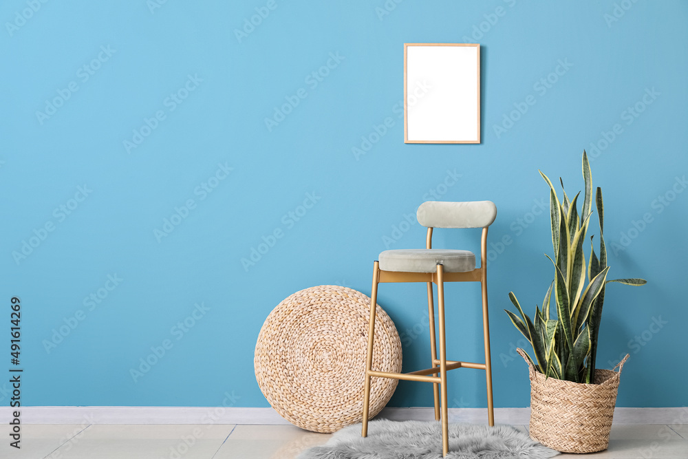 Stylish chair, blank poster and houseplant near blue wall