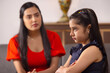 © IndiaPix - Little girl sitting with folded hands in anger and mother sitting beside