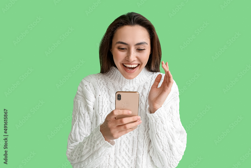 Happy woman with mobile phone reading message on green background