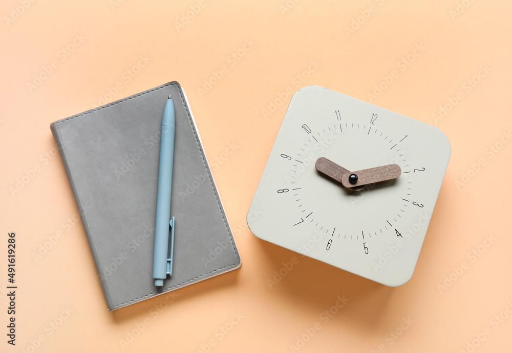 New alarm clock and notebook on color background