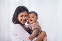 Portrait Of Happy Mother With Little Baby At Home