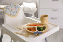 High Chair With Food In Baby Tableware On White Tray Indoors
