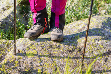 hiker wears waterproof gaiters over trekking boots walking with hiking sticks. clothing and equipmen
