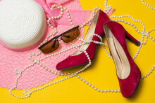 Pink Summer Women's Hat, Red Shoes, Sunglasses And Pearl Beads Lie On A Yellow Background