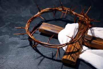 Crown of thorns with wooden cross and shroud on dark background