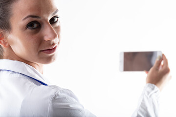 Doctor holding up her mobile phone and looking back at camera