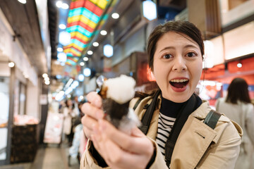 Wall Mural - female youtuber in Japan face to camera is showing the inside of sushi rice roll to her fans. asian girl holding japanese traditional food is telling person in front of her open mouth.