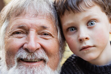 Positive Senior Man And Little Child Looking At Camera