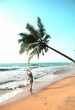  young woman stands under a palm tree on the beach . The concept of vacation and travel to the ocean. Resort on the island. paradise view . High quality photo