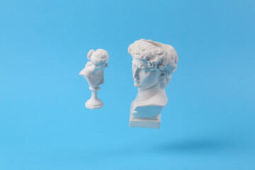 Wall Mural - Levitating Antique Plaster busts of David and Venus on blue background with shadow. Conceptual pop. Minimal still life photography