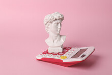 Antique David Bust With Calculator On Pink Background. Conceptual Pop. Minimal Still Life. Creative Idea