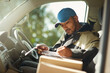 © Adene Sanchez/peopleimages.com - Updating his delivery status. Shot of a delivery man reading addresses while sitting in a delivery van.