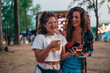 © Zamrznuti tonovi - Two beautiful friends using a smartphone on a music festival