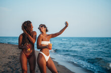 Friends Enjoying Vacation Together And Taking Selfie On The Beach Using Smartphone