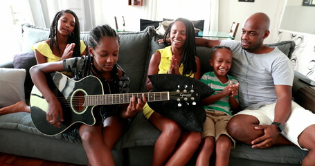  Casual black African family bonding thogether through music guitar. Daughter playing musical instrument