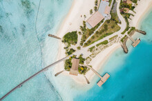 Aerial Top Down View Of Tropical Palm Trees On Island With White Sand Beach, Boat Jetty And Bridge, In South Male Atoll In Maldives.