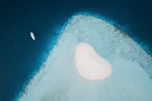 Aerial Top Down View Of Luxury Yacht Anchored Near Love Heart Shaped Island Of Sand In The Middle Of The Indian Ocean, Near Male, Maldives.
