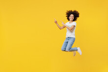 Full Body Young Woman Of African American Ethnicity Wears White Volunteer T-shirt Jump High Point Finger Aside Isolated On Plain Yellow Background. Voluntary Free Work Assistance Help Grace Concept.