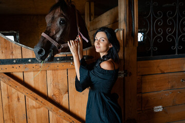 Wall Mural - Girl with long black hair in the countryside. Ipadrome with horses. Rural landscapes, wild west.