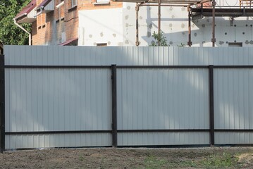 Wall Mural - part of a gray metal fence wall with a black iron frame on a rural street