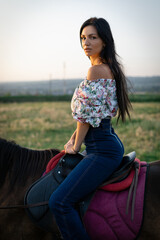 Wall Mural - Girl with long black hair in the countryside. Ipadrome with horses. Rural landscapes, wild west.