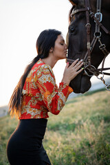 Wall Mural - Girl with long black hair in the countryside. Ipadrome with horses. Rural landscapes, wild west.