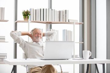 Wall Mural - senior businessman looking laptop computer and stretching on a table when taking a break