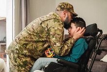 Military Soldier Father Kissing Disable Kid Son On Wheelchair During Home Returning - Family Love After US Army