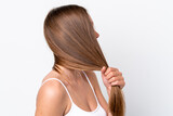 Fototapeta Zachód słońca - Young caucasian woman isolated on white background touching her hair. Close up portrait
