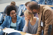 © Nicola Katie/peopleimages.com - A lecturer is always on hand if you have questions. A young man speaking to two girls sitting in a lecture room.