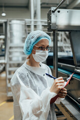 Female worker with protective face mask working in medical supplies research and production factory and checking canisters of distilled water before shipment. Inspection quality control.