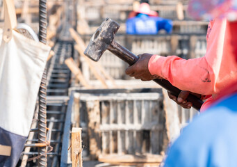 Wall Mural - The worker used a hammer to hammer a piece of wood.