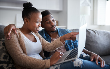 Check out this offer. Shot of a young couple using a laptop together on a sofa at home.