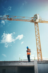 Updating project plans on the go. Shot of a young man using a smartphone while working at a construction site.