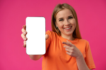 Young woman showing smartphone with isolated white screen against color background