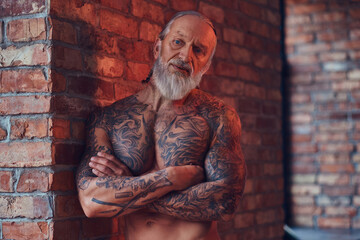 Muscular elderly man with tattooed body indoors room