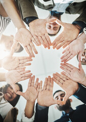 Poster - Together their brains work as one. Low angle shot of a group of cheerful businesspeople forming a huddle with their hands and looking down inside of the office.