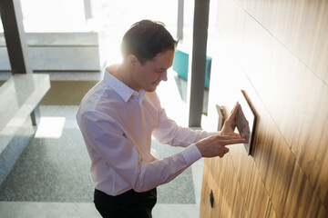 man controls smart home devices using digital tablet with launched application on background of room. concept of digitalization