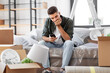 © Syda Productions - moving, eviction and real estate concept - sad man with smartphone and boxes at new home