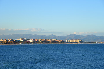 View on coastline and beach from La Marina de Valencia on the sea to the Las Arenas beach, Playa de las Arenas, Platja del Cabanyal and Playa de la Malvarrosa. Waves at sea on blue sky background.