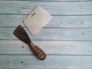 Construction :Two spoons or knives of masonry putty for metal construction and the other plastic on a wooden table.