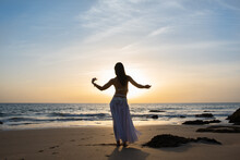 Happy And Calm Woman Poses On The Beach Wearing The Typical Belly Dance Costume. Exotic Beauty. Girl Silhouette.
