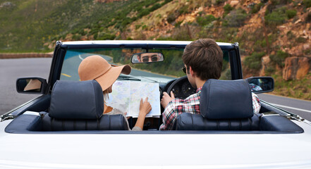 Poster - I think you shouldve turned here.... Rearview shot of a young couple reading a map while sitting in a car.