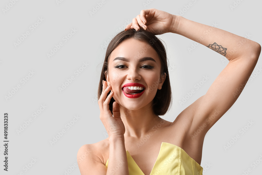 Happy woman with red lips showing tongue on light background