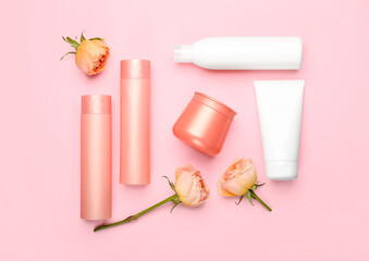 Set of cosmetic products and rose flowers on pink background