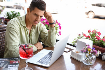 Poster - Handsome young man working with laptop in street cafe